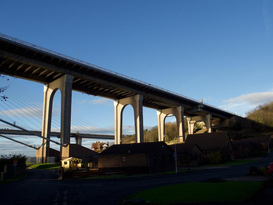 A series of arched bridge supports rising up above some houses.